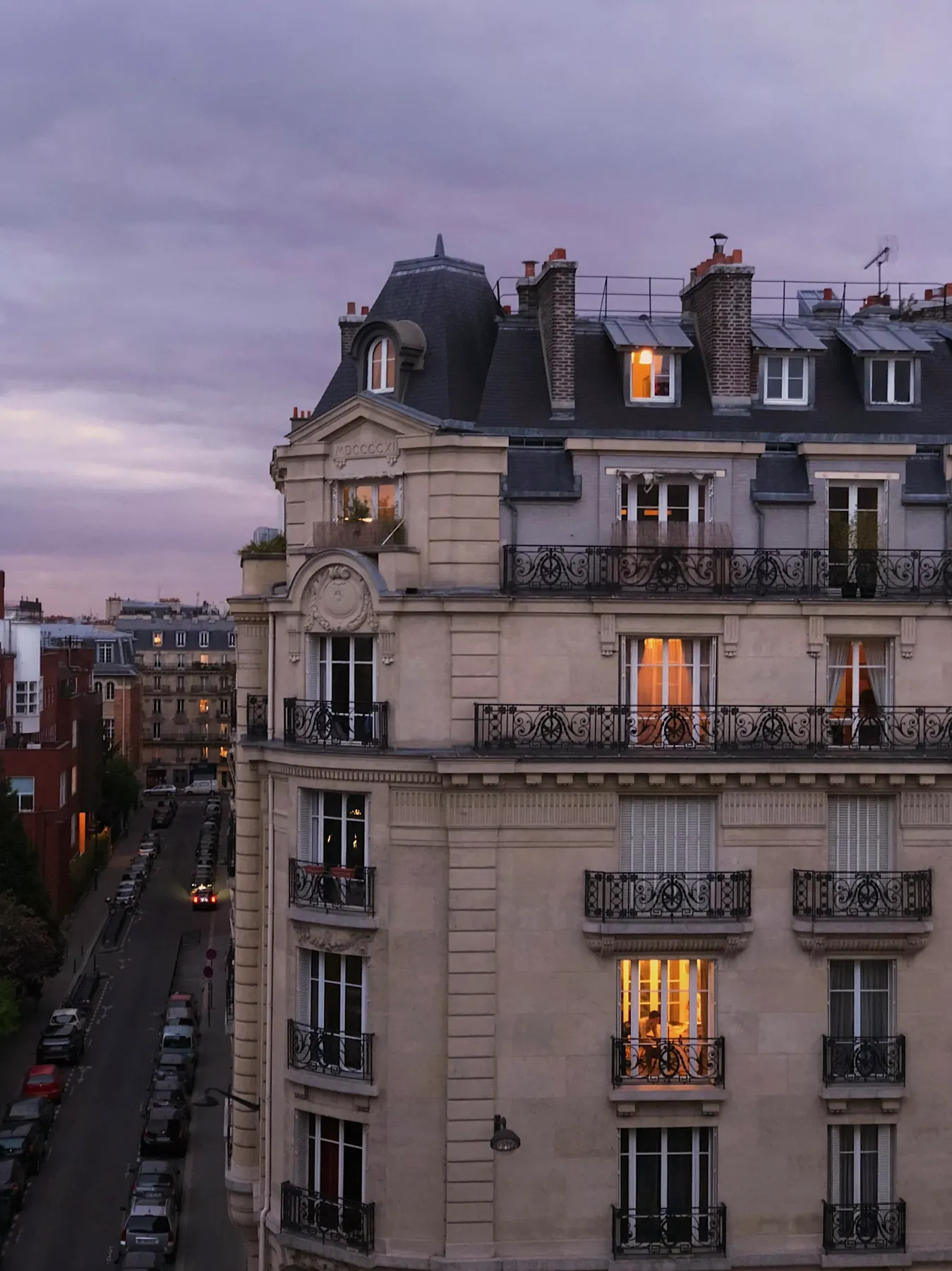 Façade haussmannienne au crépuscule, quelques fenêtres allumées